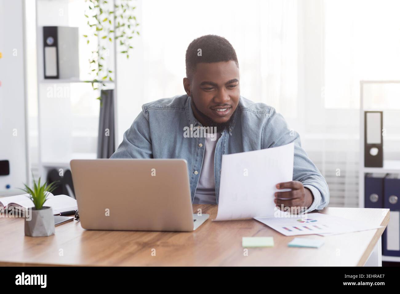 Black businessman working with documents in office, checking financial reports Stock Photo