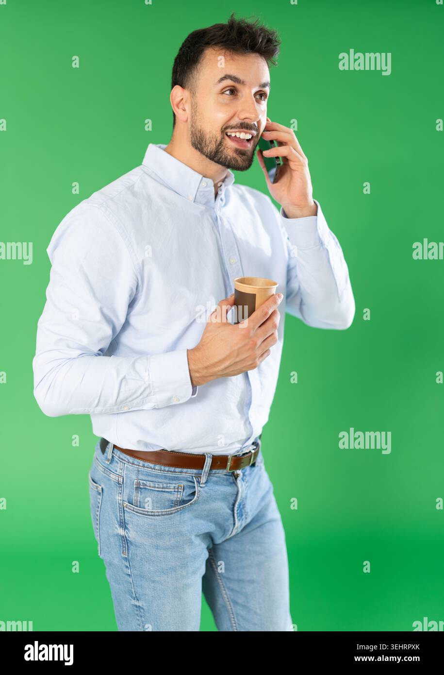Man with cup of coffee is talking on phone, emotionally communicating with friend Stock Photo