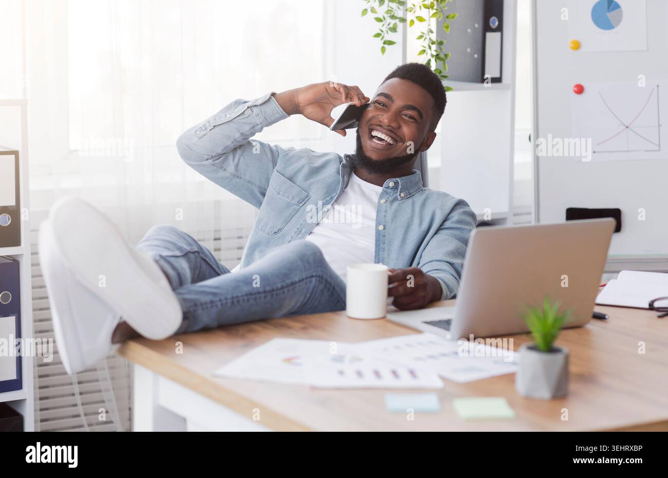 Joyful black manager talking on phone while having break at work Stock Photo
