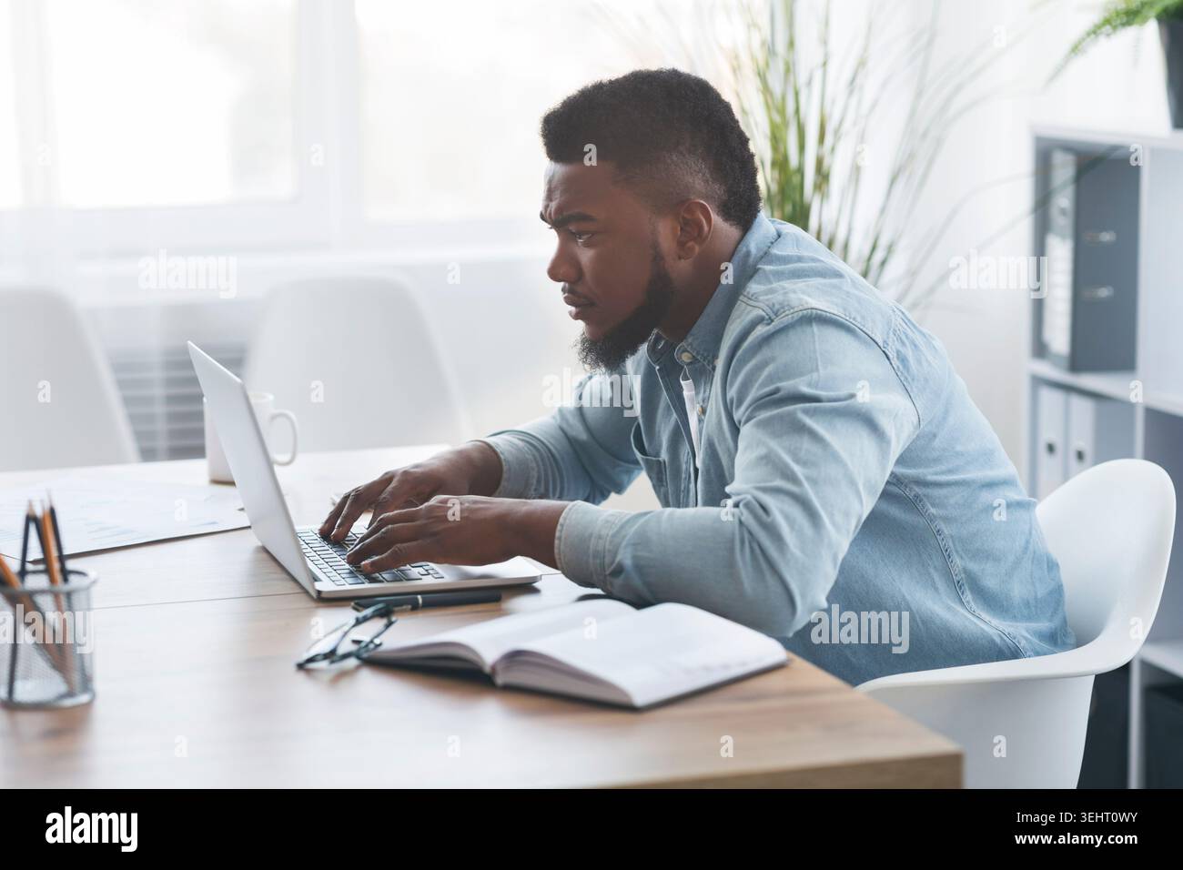 Concentrated young african worker using laptop in office Stock Photo