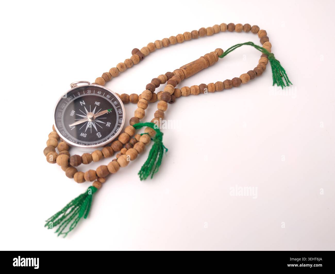 Compass On String A silver magnetic compass intertwined with a string of wooden prayer ...