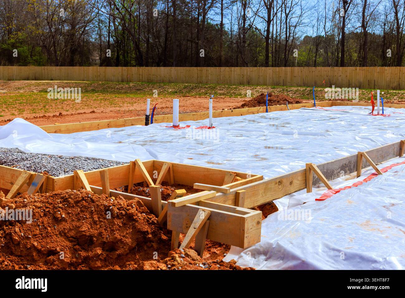 Construction workers prepare foundation by setting wooden forms laying plastic sheeting Stock Photo