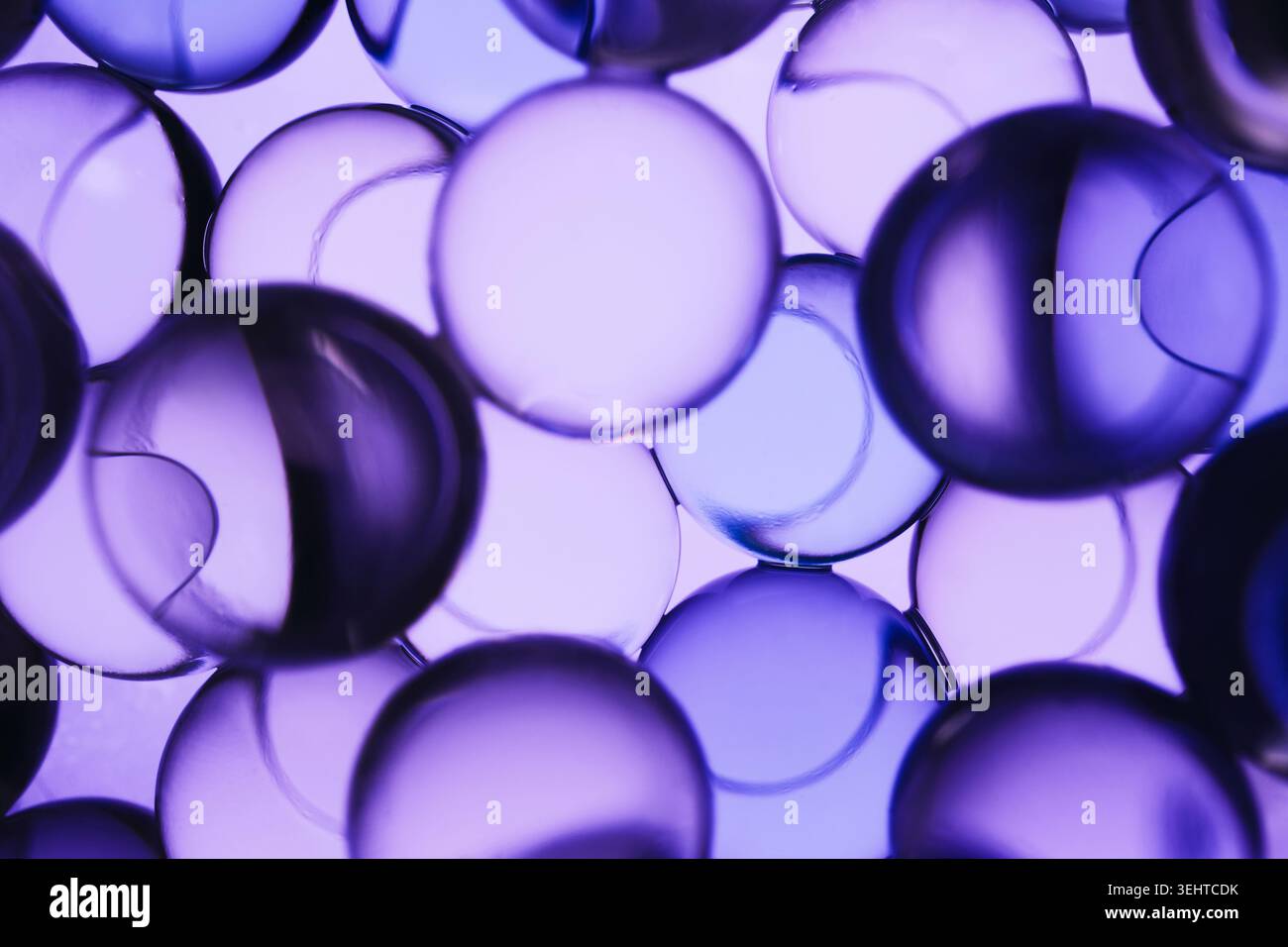 Multiple transparent liquid spheres creating vibrant purple science abstract background Stock Photo