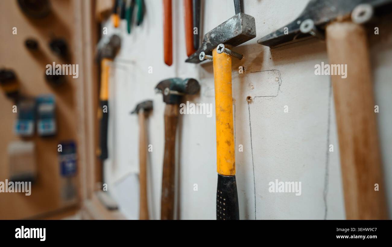 Hammers and other work tools neatly arranged on a workshop wall Stock Photo