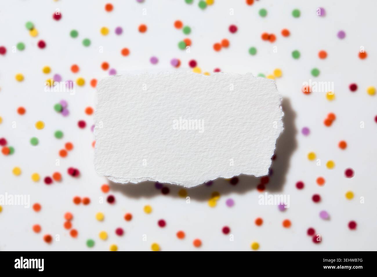 Torn white paper on confetti background Stock Photo