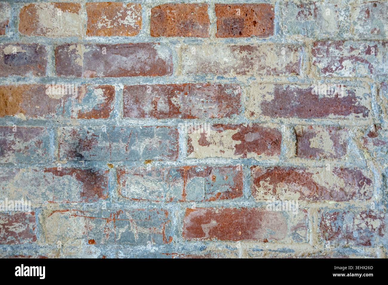 Close up view of rustic brick wall with peeling blue or teal paint. Stock Photo