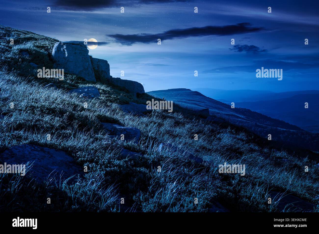 mountain landscape in summer at night. mysterious outdoor scenery of carpathian mountains. full moon over grassy slopes with rocks. fantasy image for Stock Photo