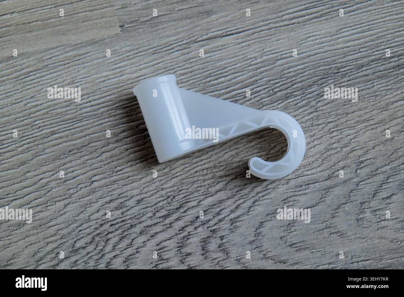 White plastic hook on wooden floor Stock Photo