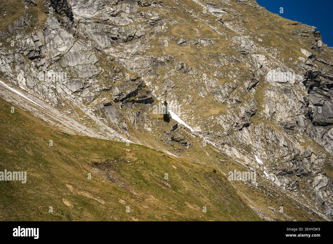 Rugged alpine mountain slope with exposed rock, grassy ledges and a ...