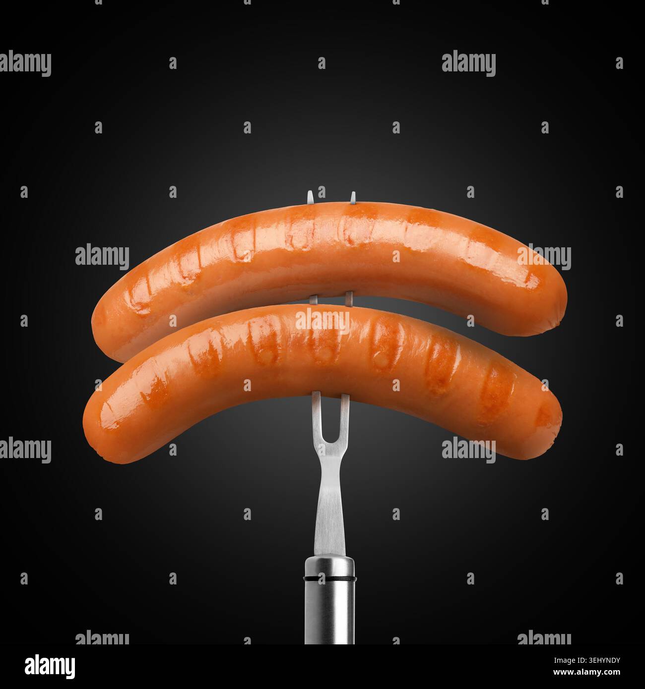 Delicious grilled meat sausages on fork against black gradient background Stock Photo