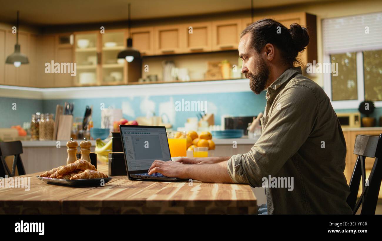 Software developer at home, writing code and debugging applications, IT engineering on command-line interfaces. Focused digital work ensures software maintenance, laptop in the kitchen. Stock Photo