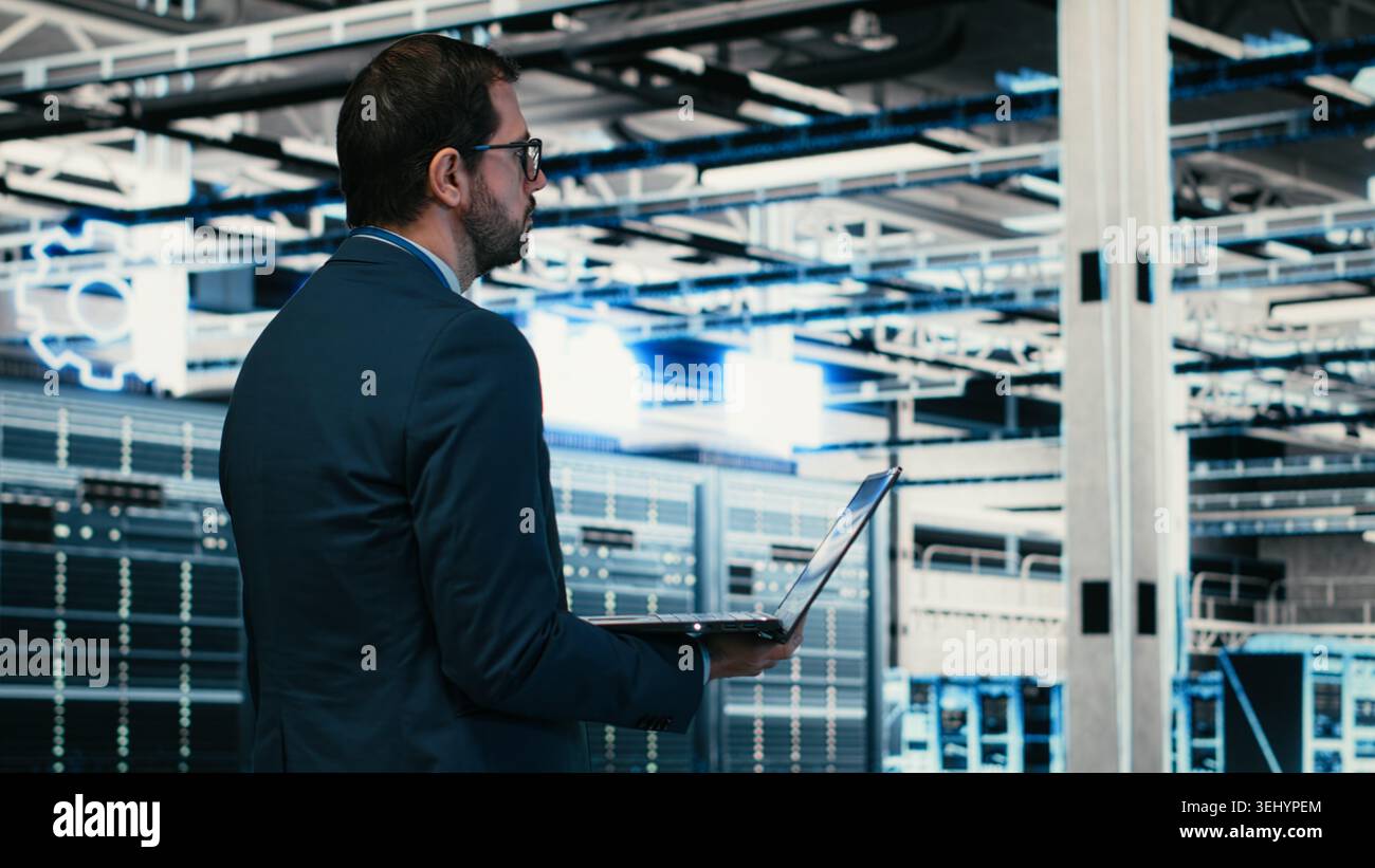 Writing code, laptop program and software developer in data center doing resource optimization. Upgrading IT infrastructure, programming script on notebook worker walking in server hub, camera B Stock Photo