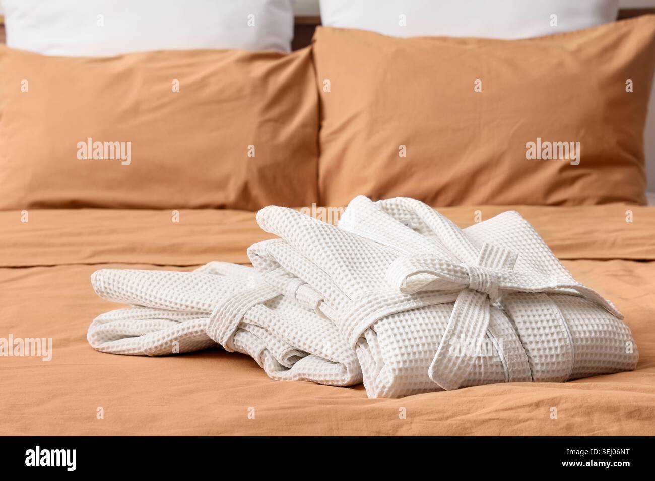 Folded waffle bathrobes on bed in room Stock Photo