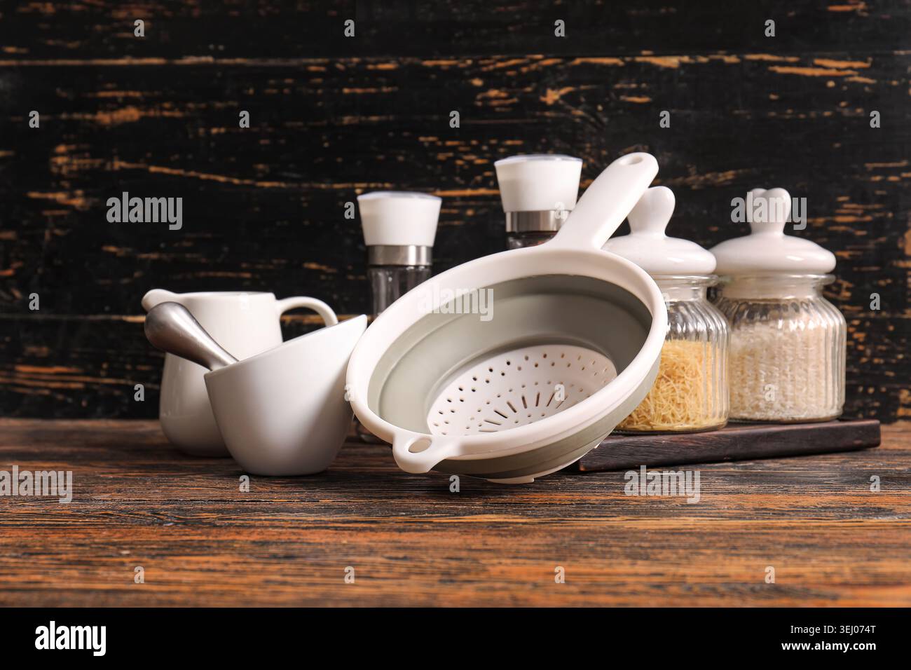 Colander with different kitchen utensils on wooden background Stock ...