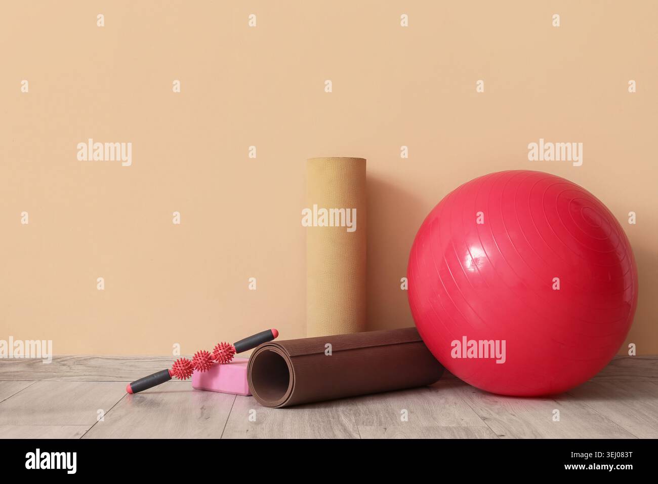 Set of sports equipment with fitness ball on floor near color wall ...