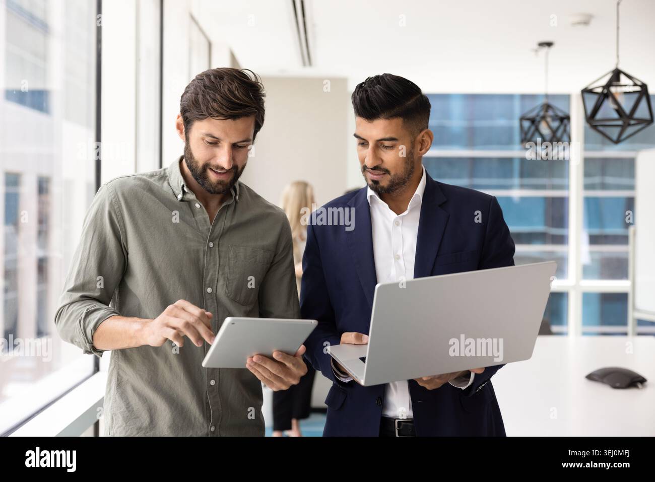 Team collaborating using digital devices in modern office Stock Photo