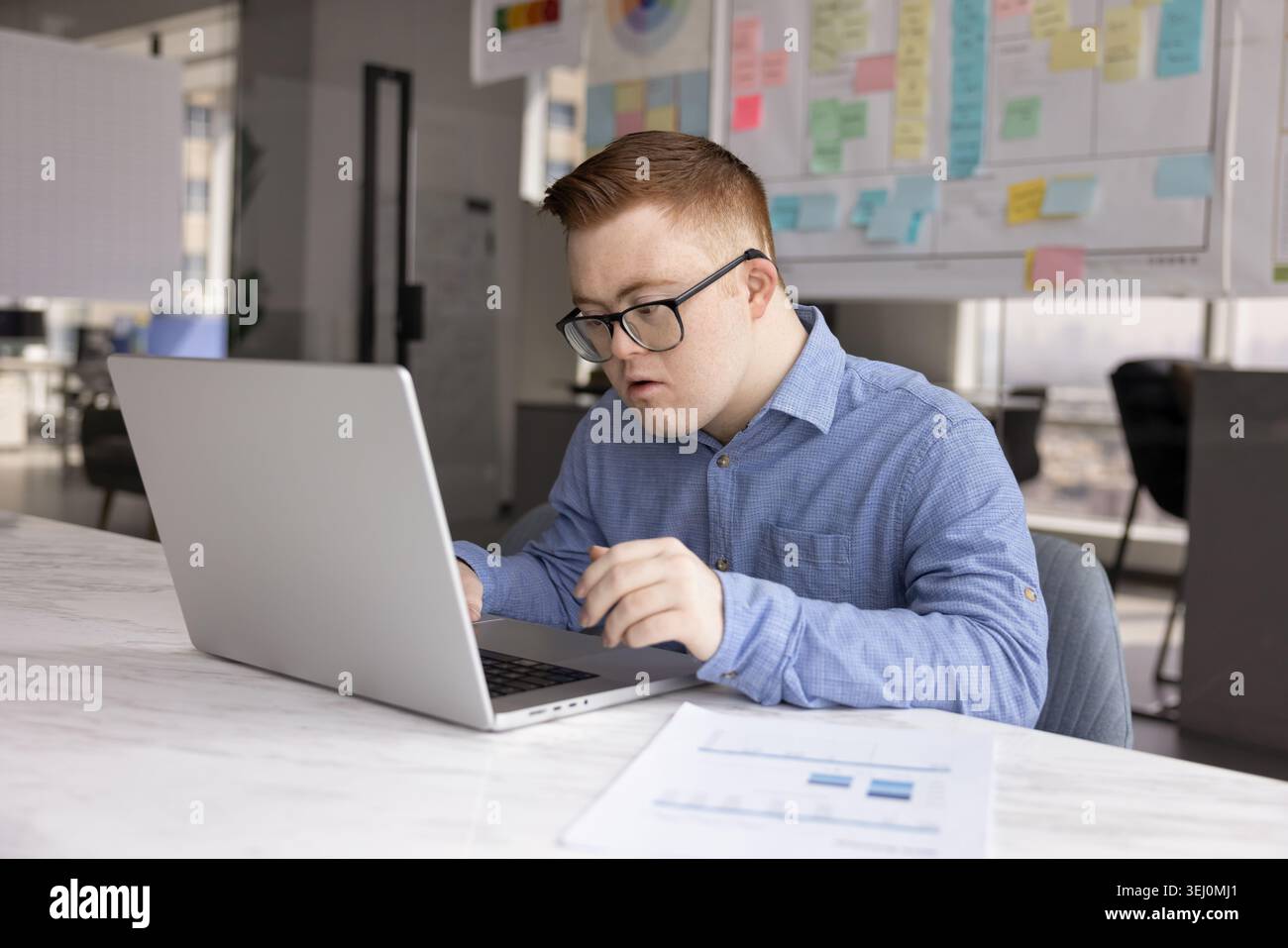 Young man with Down syndrome working in office Stock Photo