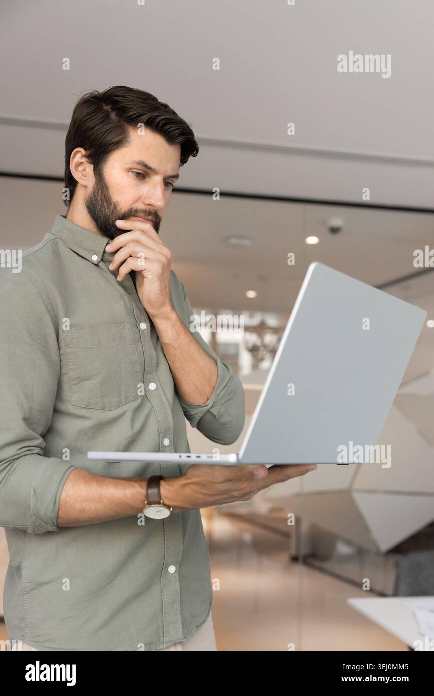 Focused businessman analyzing financial data on laptop Stock Photo