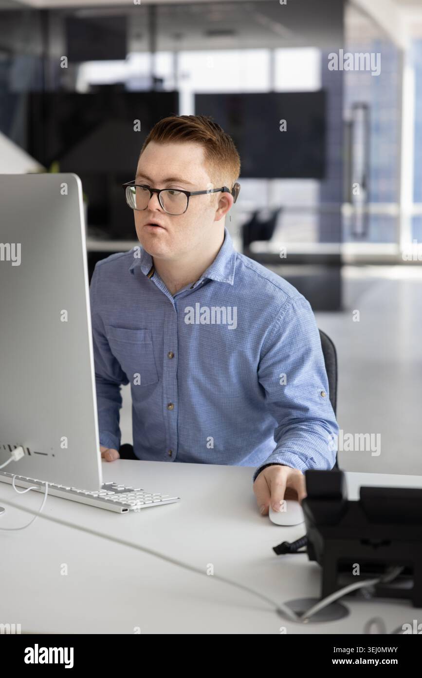 Young man with Down syndrome working on computer in office Stock Photo