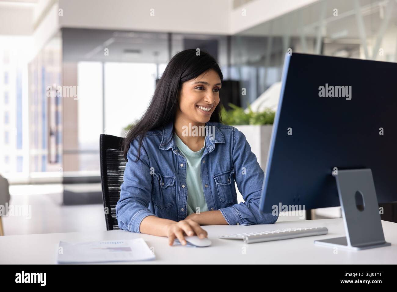 Young smiling woman focused in productive workflow using pc Stock Photo