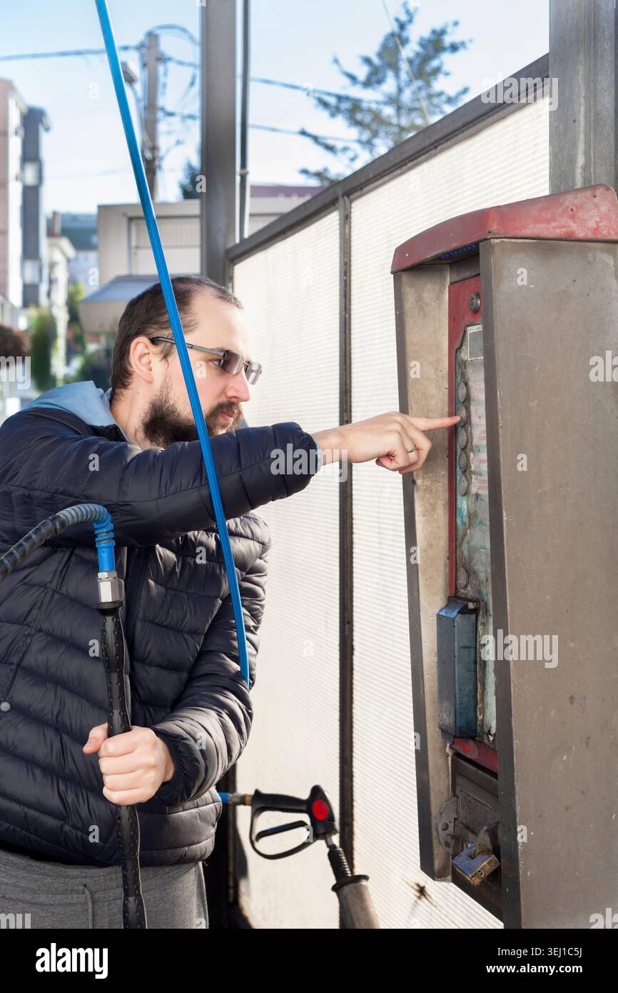 Man using self service car wash control panel outdoors Stock Photo