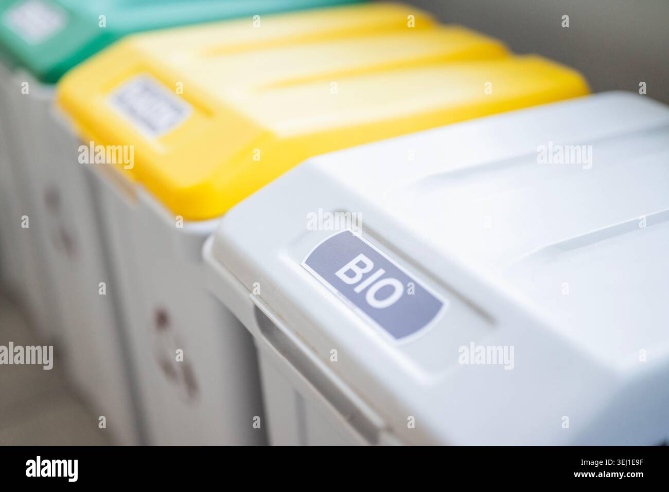 A close-up view of color-coded recycling bins, highlighting a yellow ...