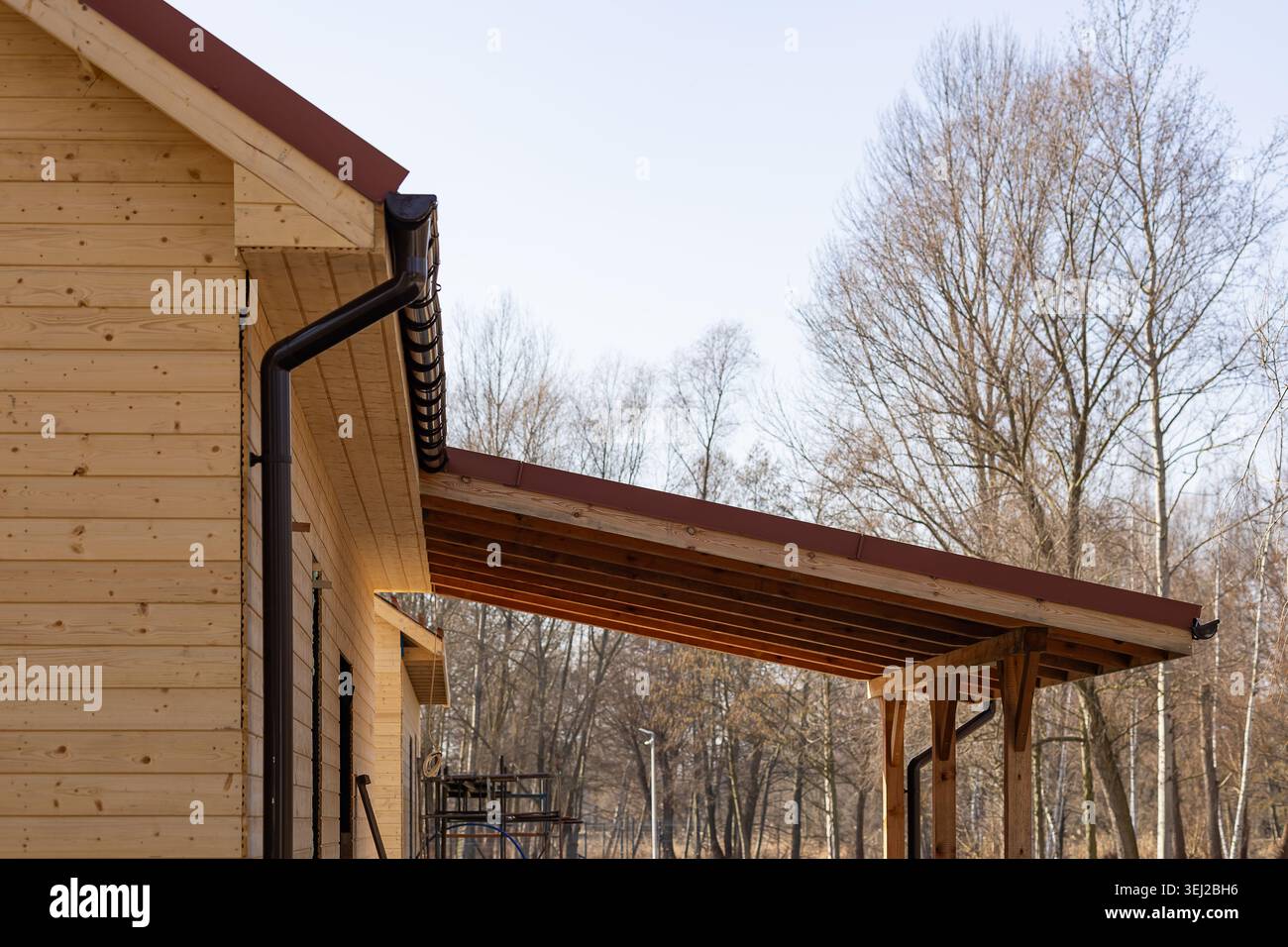 Timber Gutter Wooden house facade with brown plastic gutter system and car canopy ...