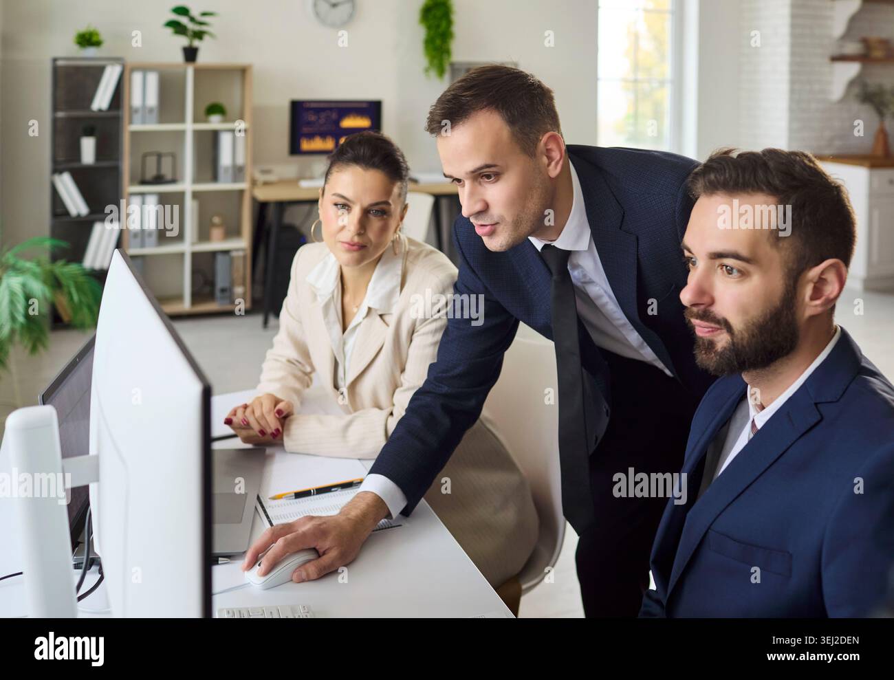 Business team analyzing data on computer in office, planning strategy together Stock Photo