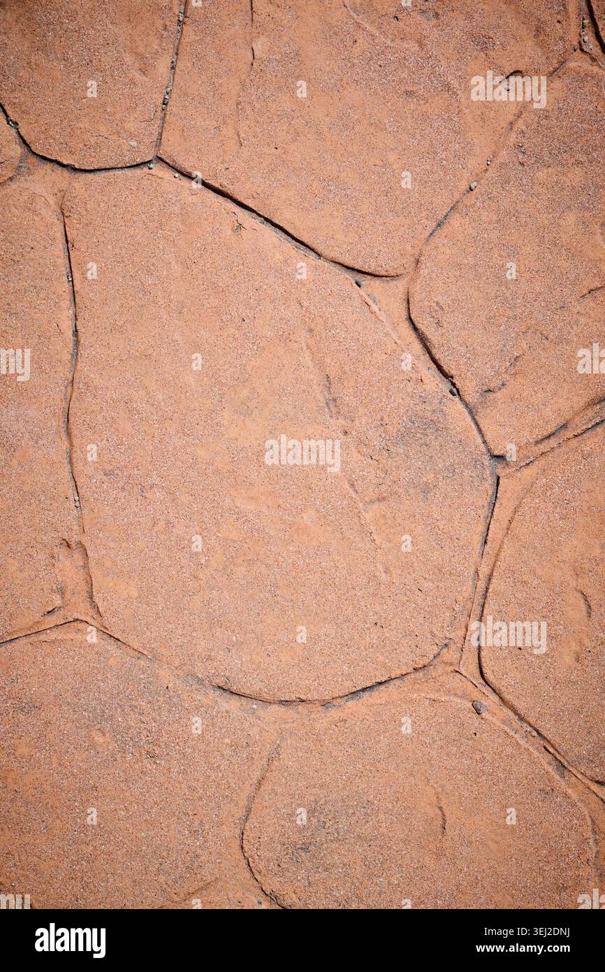 Sidewalk made of stamped concrete in an orange-brown color with an irregular stone pattern. Stock Photo