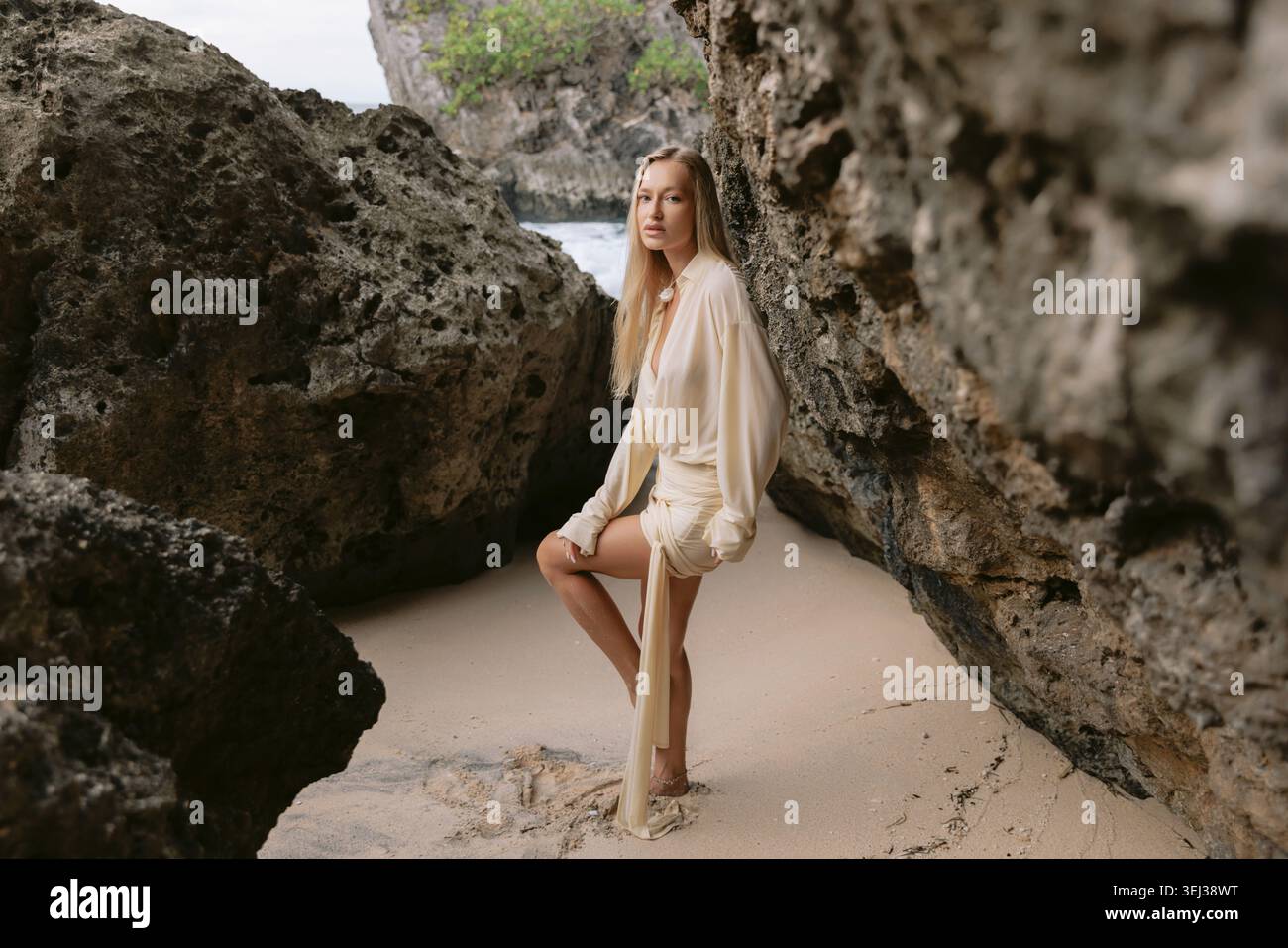 Woman posing on sandy beach between rocks Stock Photo
