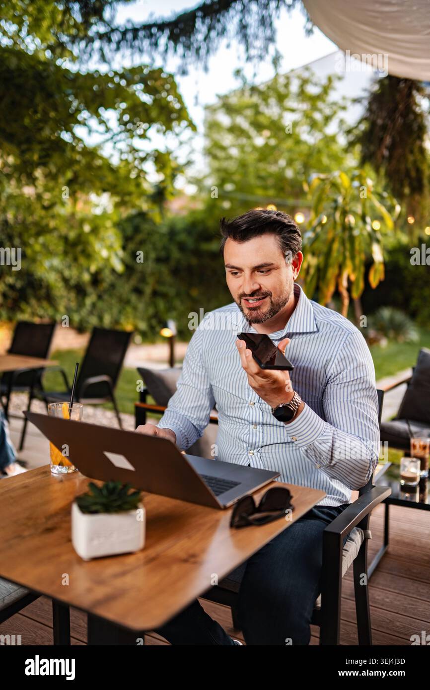 Man working remotely using laptop and voice message Stock Photo