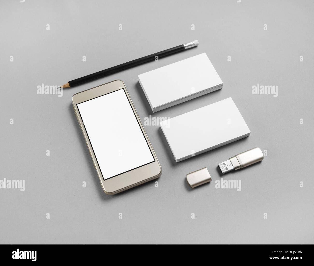 Cellphone and stationery on gray paper background. Blank business cards, pencil, smartphone and usb flash drive Stock Photo