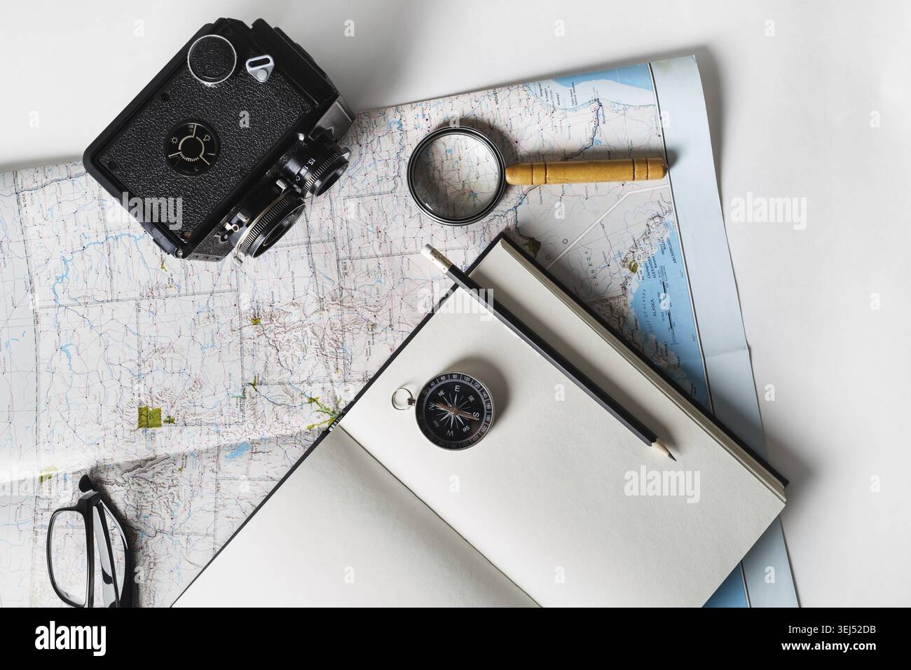 Making a travel plan. Map, blank notepad, camera, magnifier, compass, pencil and glasses. Flat lay Stock Photo