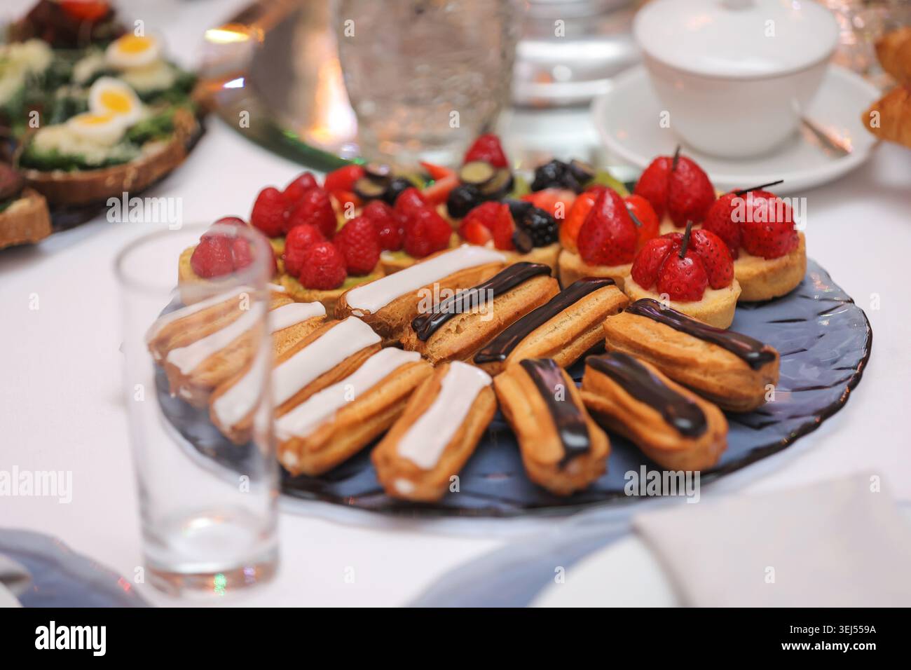 Mini Eclairs and Fruit Tarts on Dessert Platter Stock Photo