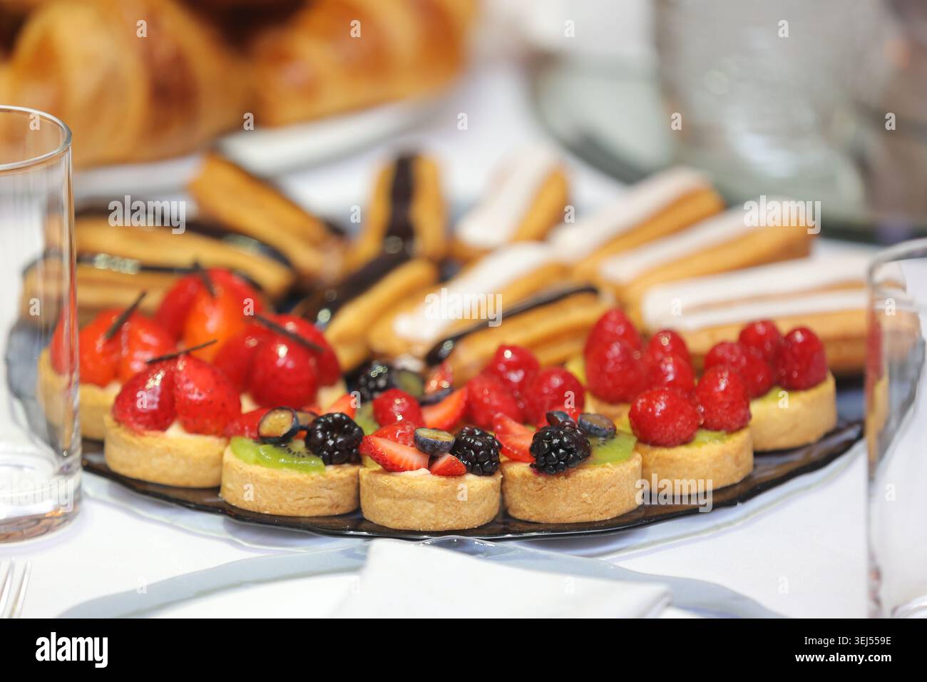 Assorted Mini Fruit Tarts and Eclairs on Dessert Platter Stock Photo