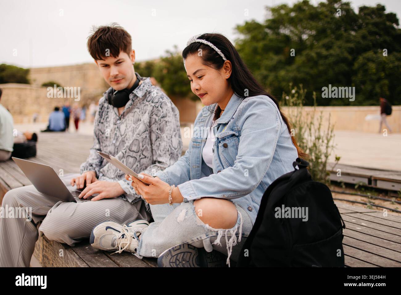 Students using laptop and studying together outdoors Stock Photo