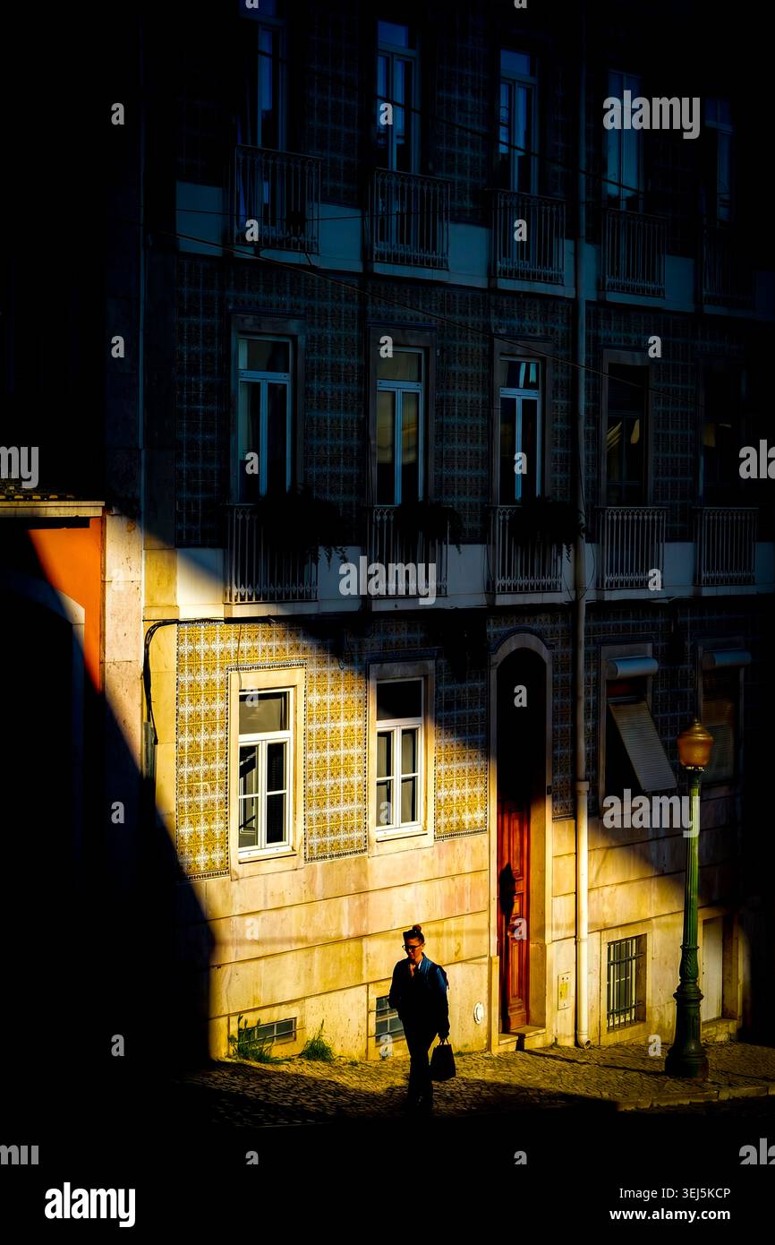 Cinematic chiaroscuro: lone figure caught in dramatic shaft of light, Lisbon, Portugal Stock Photo