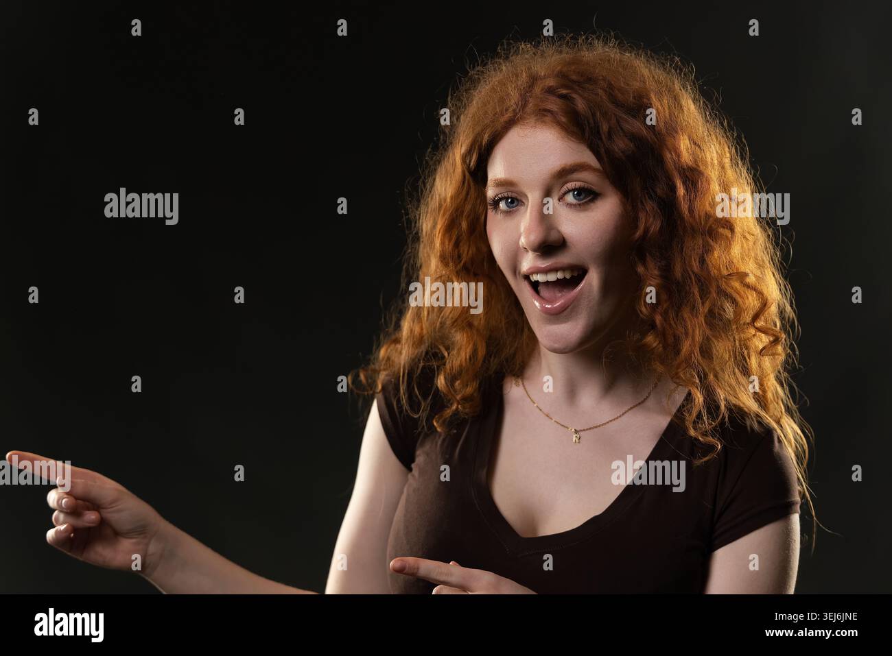 Redhead woman with curly hair pointing looking excited and surprised Stock Photo
