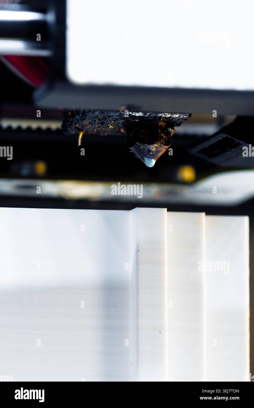 3D printer nozzle creating object in workshop during day Stock Photo