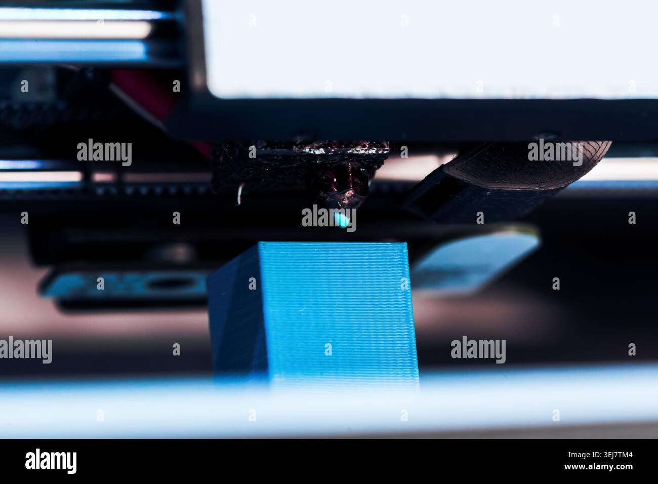 3D printer working on creating a blue object at close range in a workshop setting Stock Photo