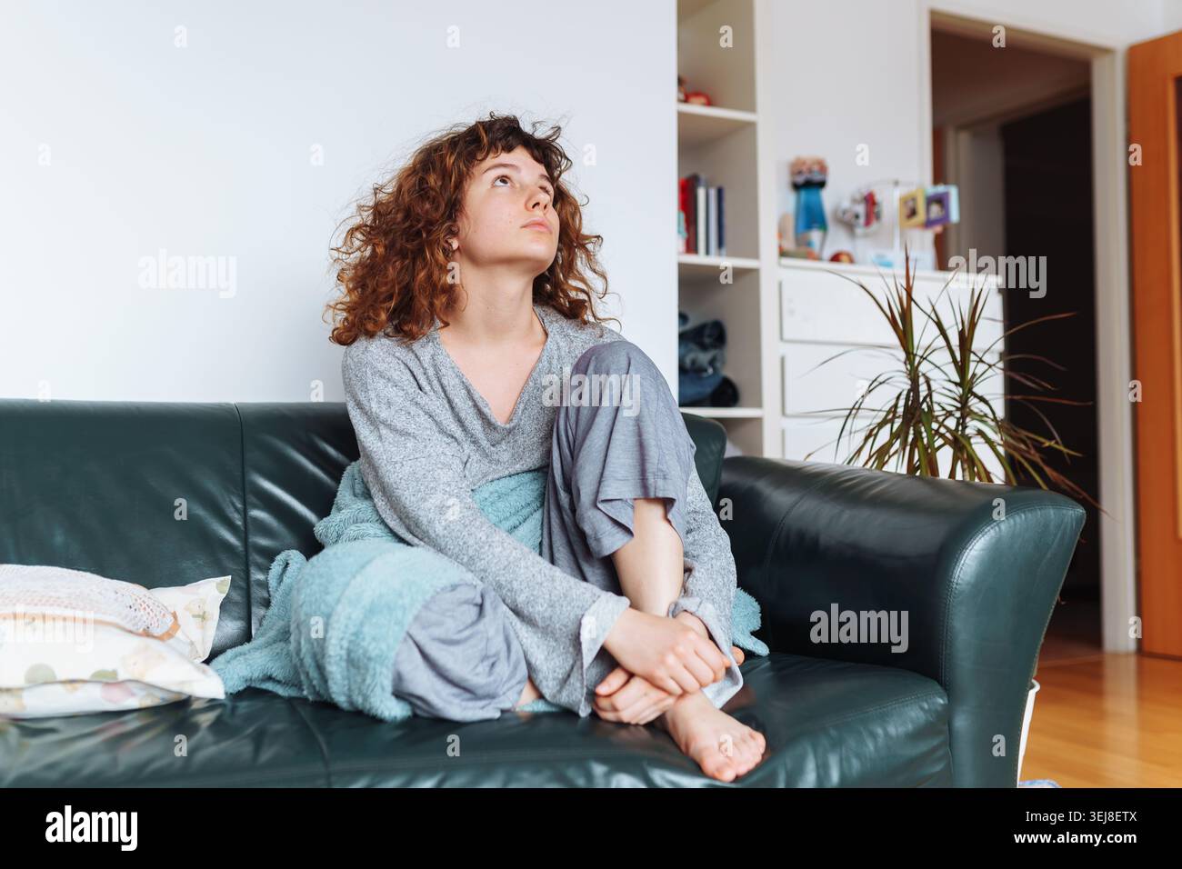 young red-haired woman relaxing on leather sofa Stock Photo