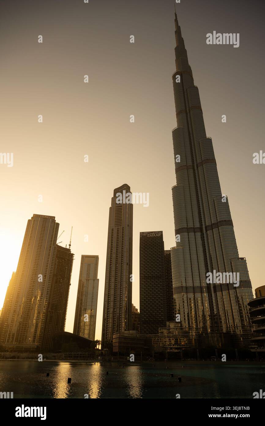 A vertical low-angle shot of the iconic Burj Khalifa and the surrounding skyline in Downtown Dubai during the golden hour. The world's tallest buildin Stock Photo