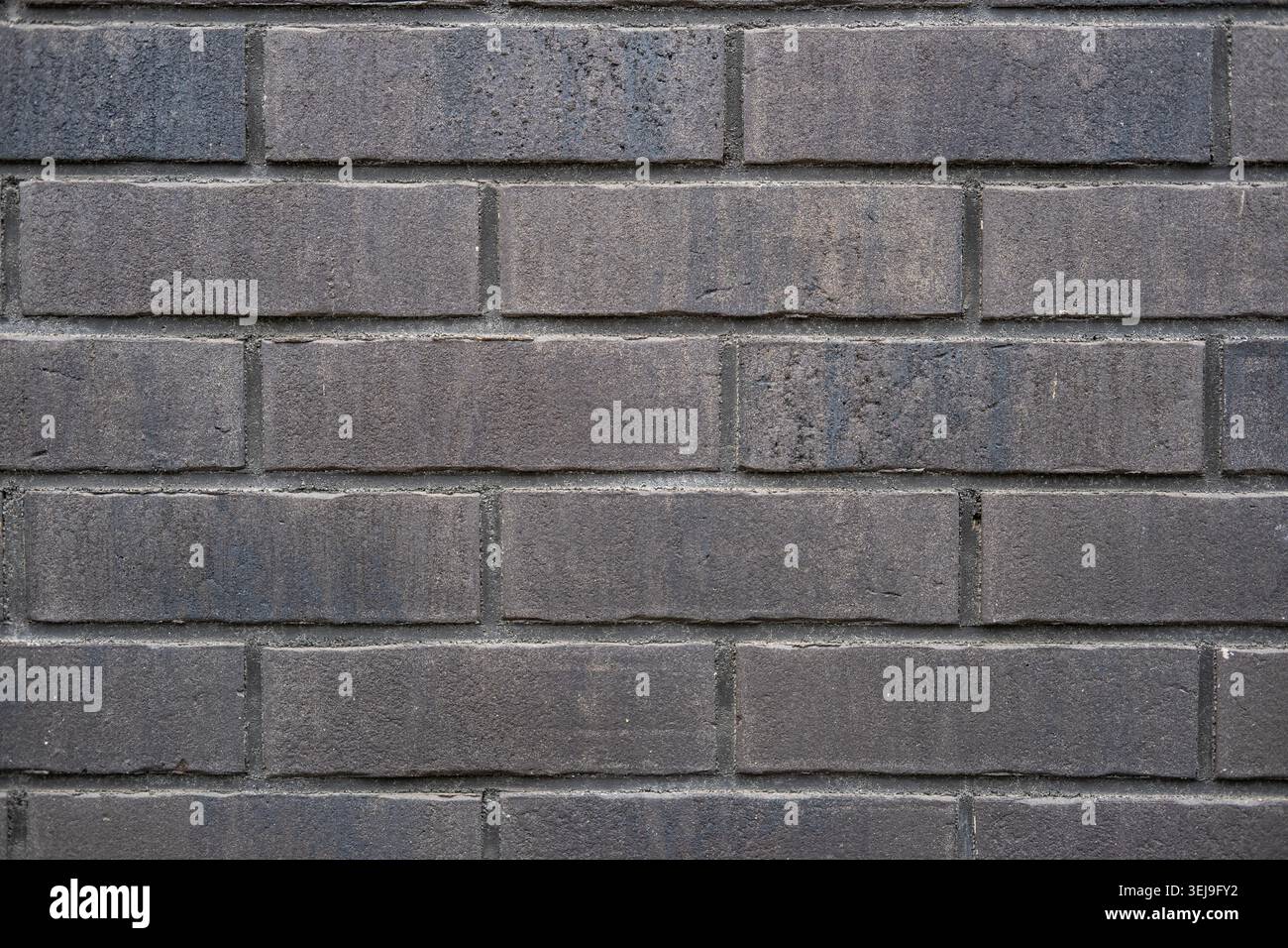 Close up of a wall built with dark grey rectangular bricks. Stock Photo