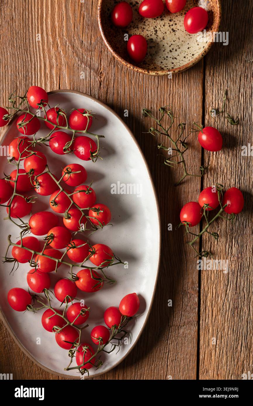 Grape tomatoes on the vine on rustic wooden surface Stock Photo