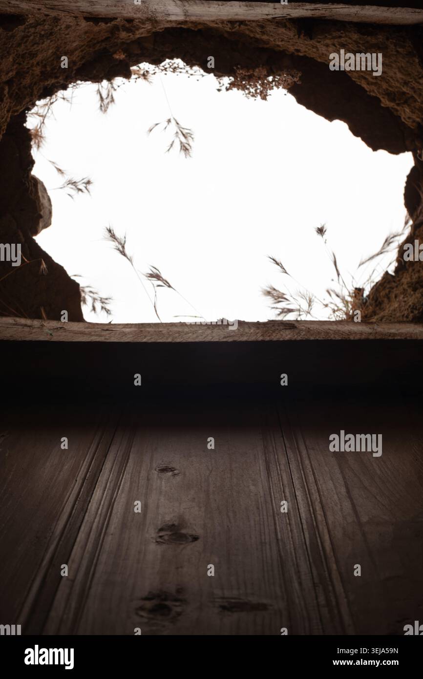 A vertically composed photograph captures an oval structural hole in a collapsed stone and compacted earth ceiling. Stock Photo