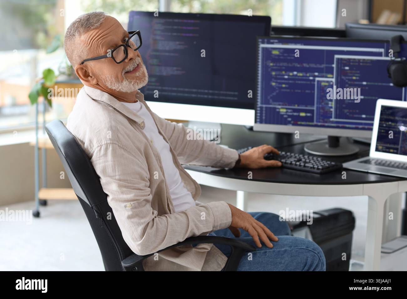 Mature programmer working with computer at table in office Stock Photo