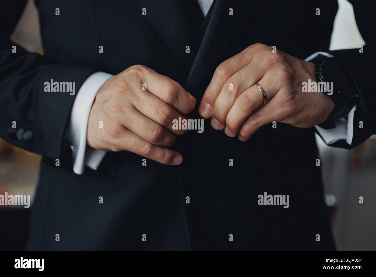 Man in dark suit buttons jacket with care Stock Photo