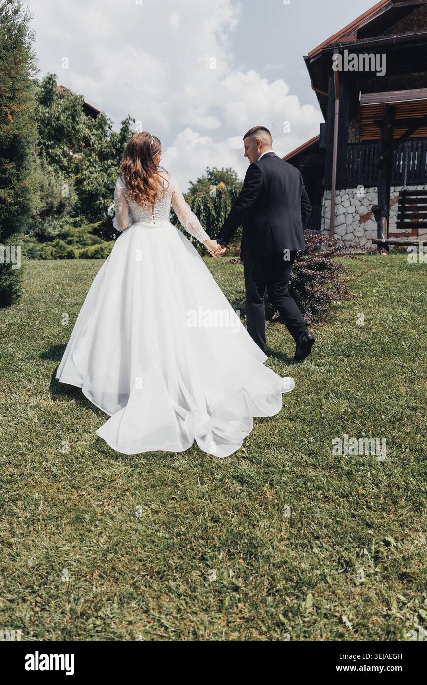 Young couple walks hand in hand through green grass Stock Photo