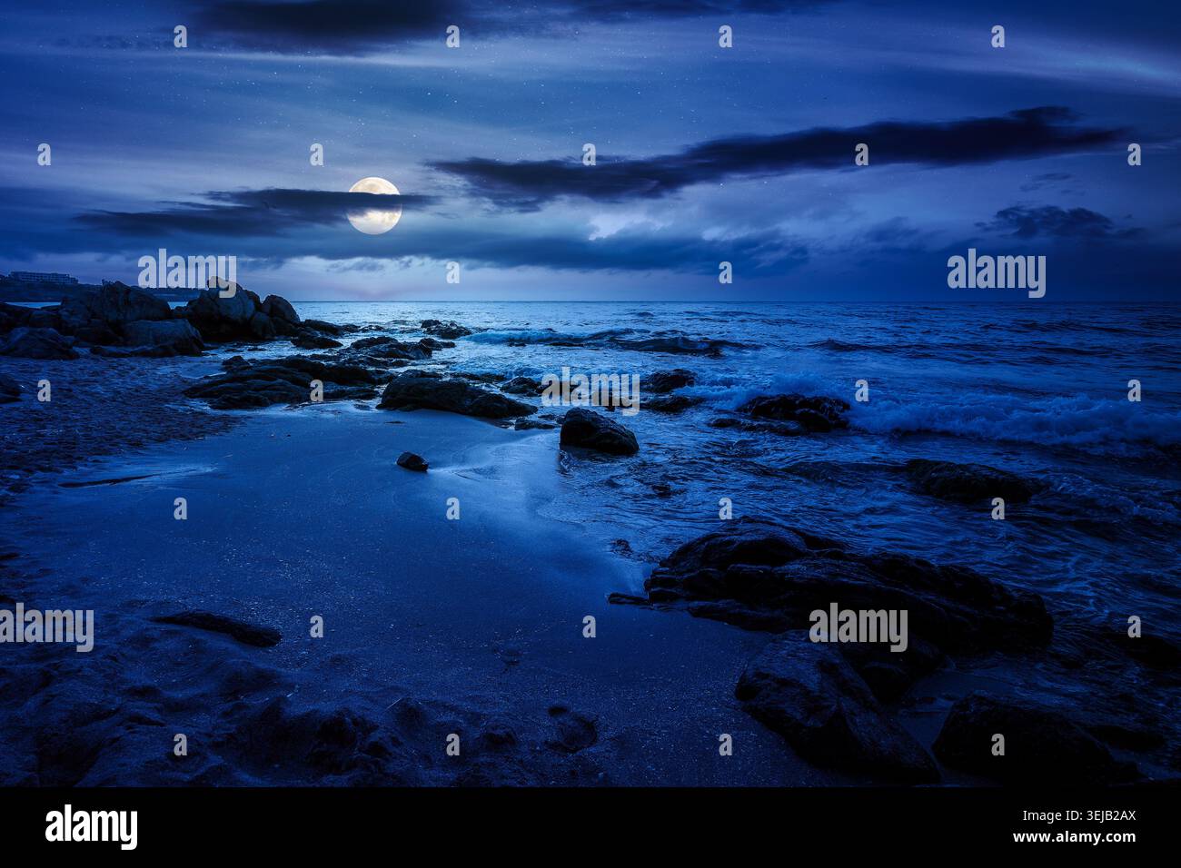 huge stones on a sandy beach at night. wonderful summer vacation season at the black sea. full moon over calm waves washing the sand shore. mysterious Stock Photo