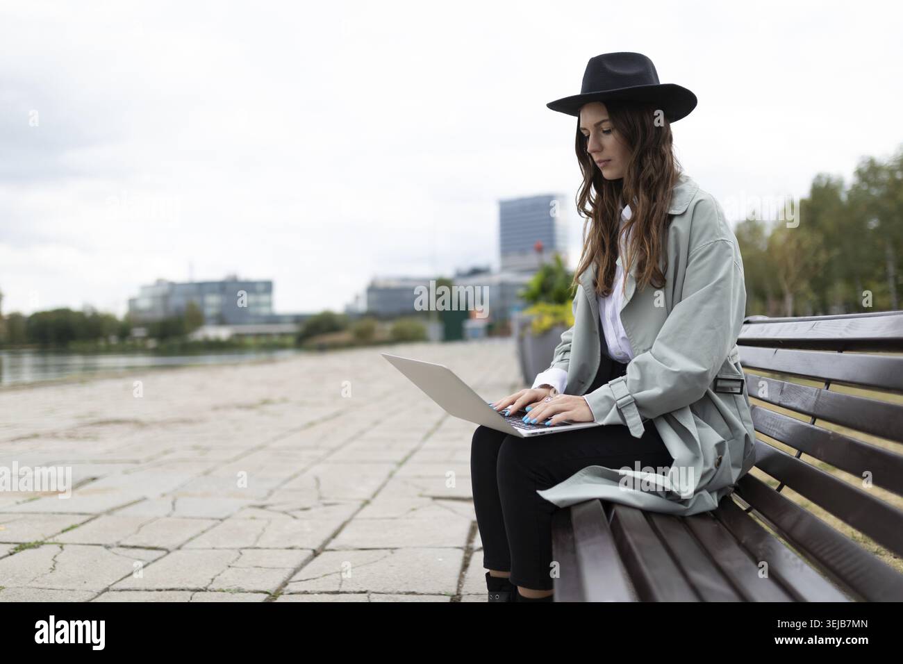 Young strong woman freelancer software developer working on laptop outside Stock Photo